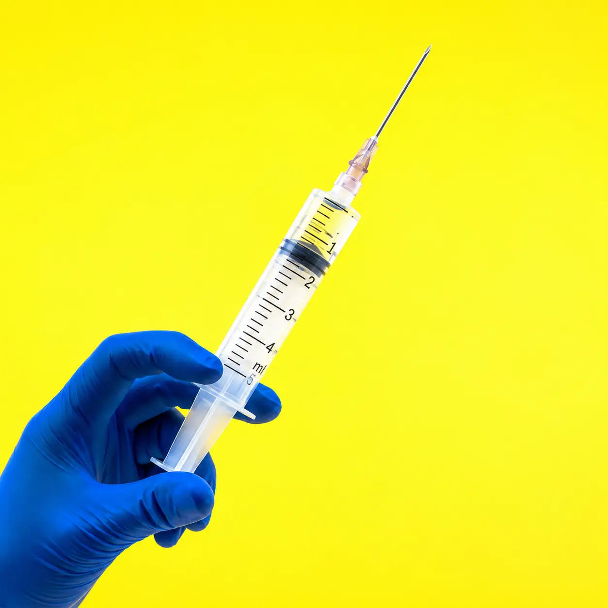 Gloved hand holding a syringe, representing mRNA therapeutics manufacturing in North America