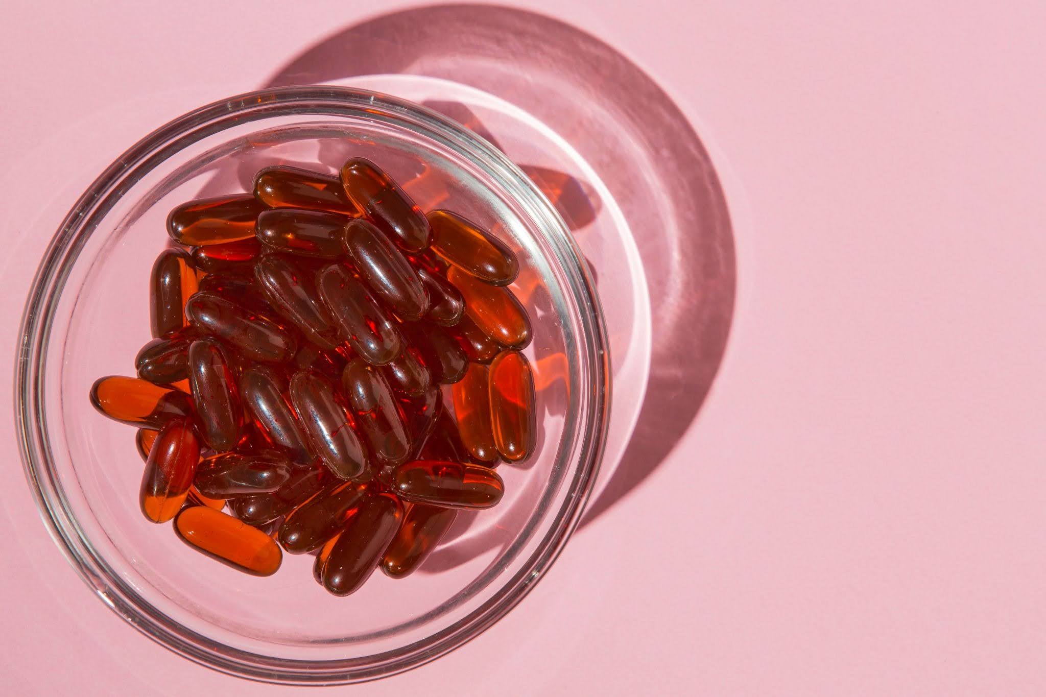 Close-up of red softgel capsules in a glass bowl
